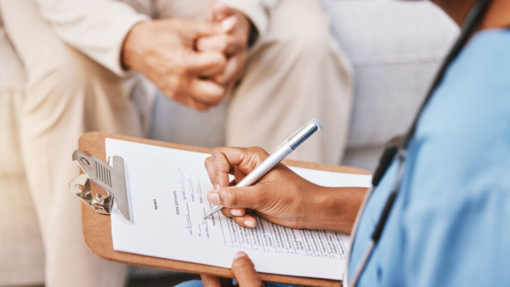 Doctor writing notes during patient consultation.
